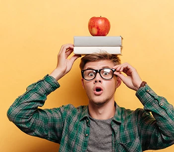Erstaunter Mann mit Buch und Apfel auf dem Kopf