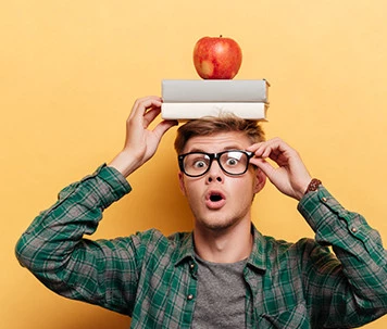 Erstaunter Mann mit Buch und Apfel auf dem Kopf