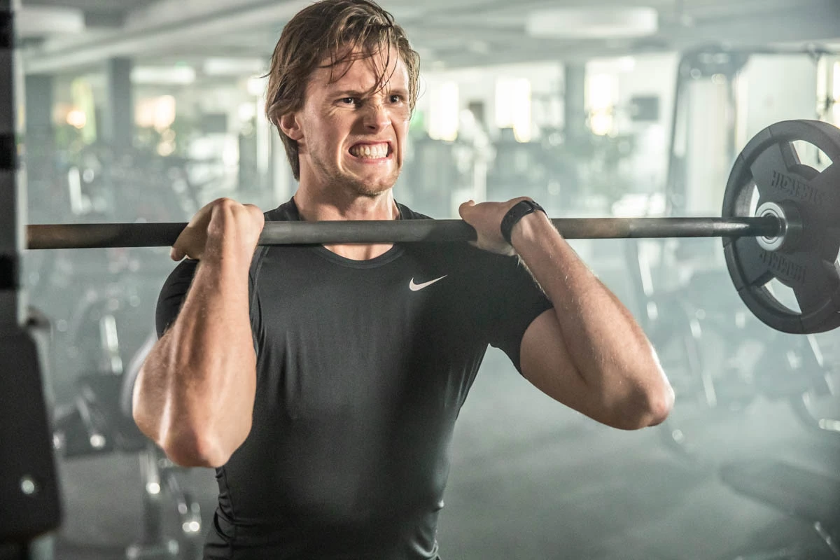 Mann mit Langhantel trainiert Oberkörper