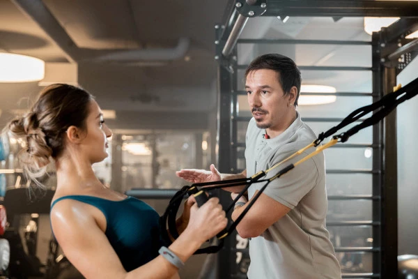 Functional Training Frau mit Trainer am TRX