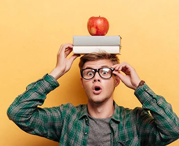 Erstaunter Mann mit Buch und Apfel auf dem Kopf