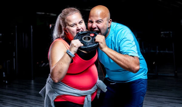 Trainingsziel Abnehmen Pärchen beißt motiviert in Hantelscheibe