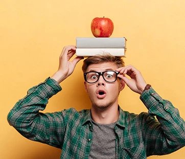 Erstaunter Mann mit Buch und Apfel auf dem Kopf
